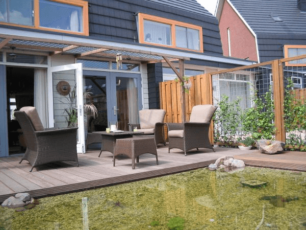 Achtertuin met houten vlonder, vijver, loungeset en pergola bij moderne woning — Van der Velden & Willemse