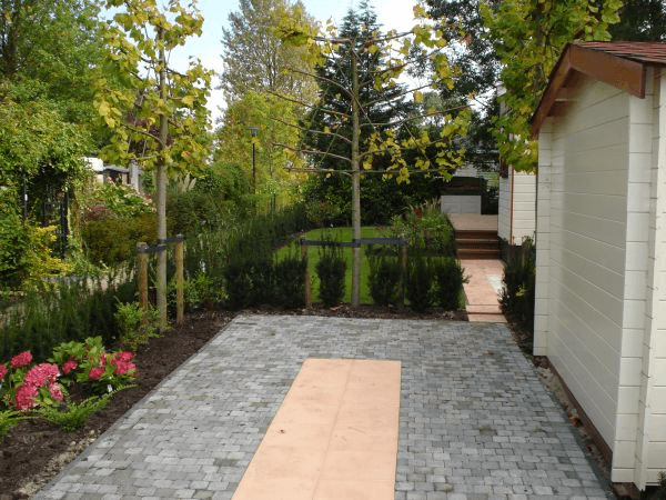 Sierbestrating met middenstrip, jonge bomen en gazon richting vlonder.