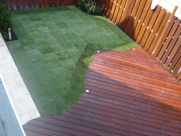 Luchtfoto: gazon, gebogen vlonder met spotjes en sierbestrating.