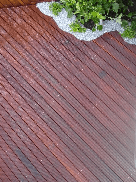 Detail organische boord tussen vlonder en grindborder met groen.