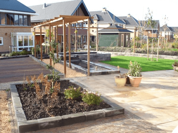 Tuin met waterpartijen onder pergola, houten vlonder, gazon en grote terrastegels.