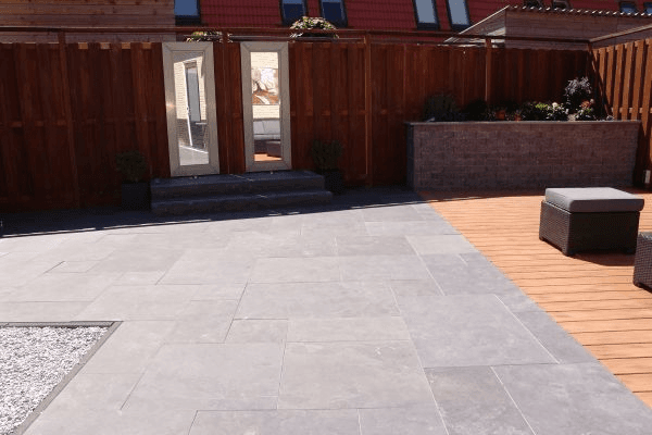 Modern terras met grote grijze tegels, vlonder, lounge en spiegelpanelen in schutting.